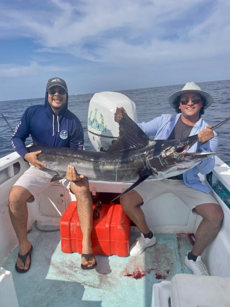 Angler holding a striped marlin during a full day offshore fishing charter in San José del Cabo