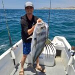 Fisherman proudly holding a trophy roosterfish during inshore fishing in San José del Cabo.