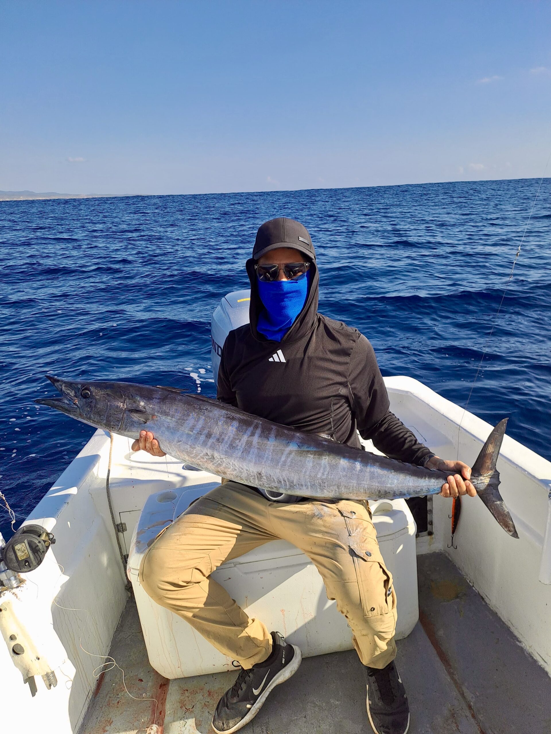 Couple holding fresh wahoo with marina background