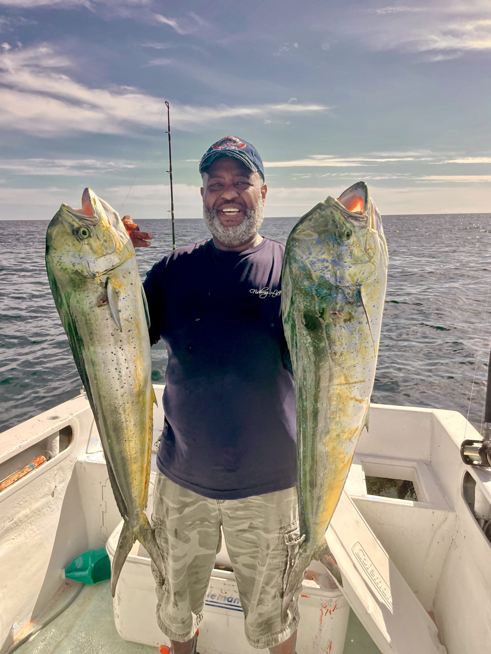 Angler lifting a bright green mahi mahi on the deck of a Daliken charter boat